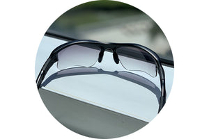 View of a pair of sunglasses with gray gradient lenses installed sitting on a window frame.